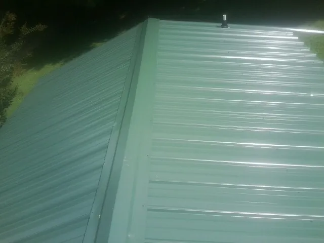 New green metal panels meeting at the ridge of a roof — Flat Roof Repair work by our crew in Vidalia