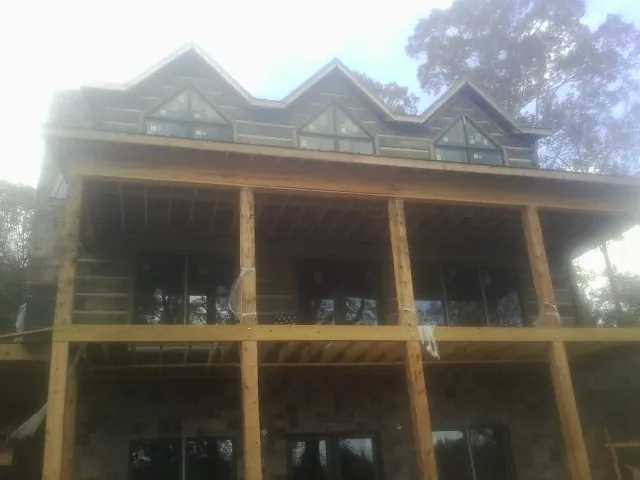 Dormers and porch framing on a large log home under construction — Roof Coating work by our crew in Vidalia