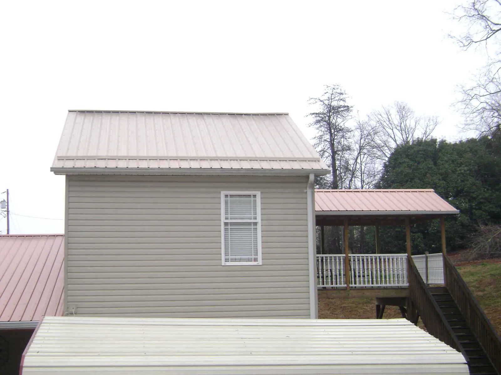 Tan metal roofs on a two story addition and attached porch, from a Roof Replacement job in Vidalia